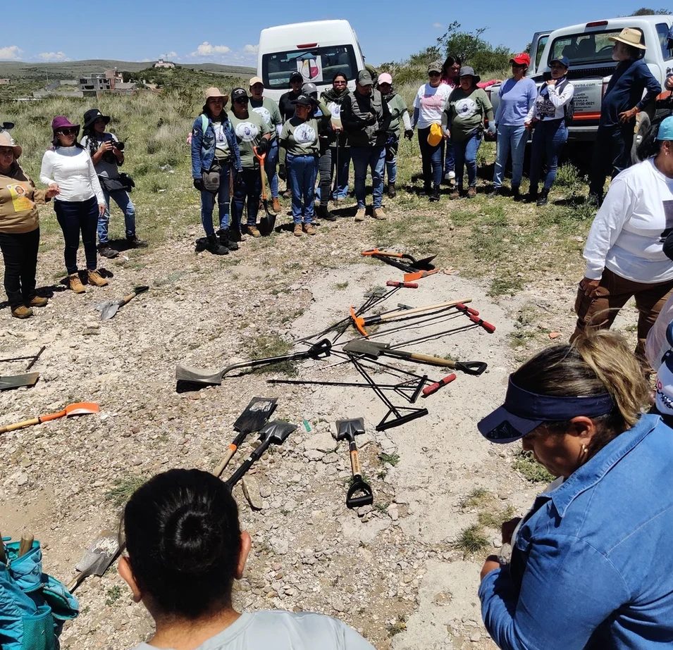 Searching mothers gathered in a circle around their shovels and probes before a search