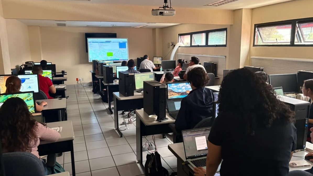 Knowledge exchange workshop: participants at computers following a geospatial search platform on a projected screen